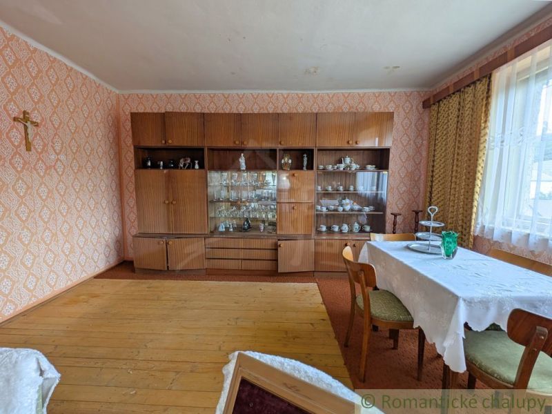 Living room in a family house with furniture, wooden decor flooring, and a dining table.
