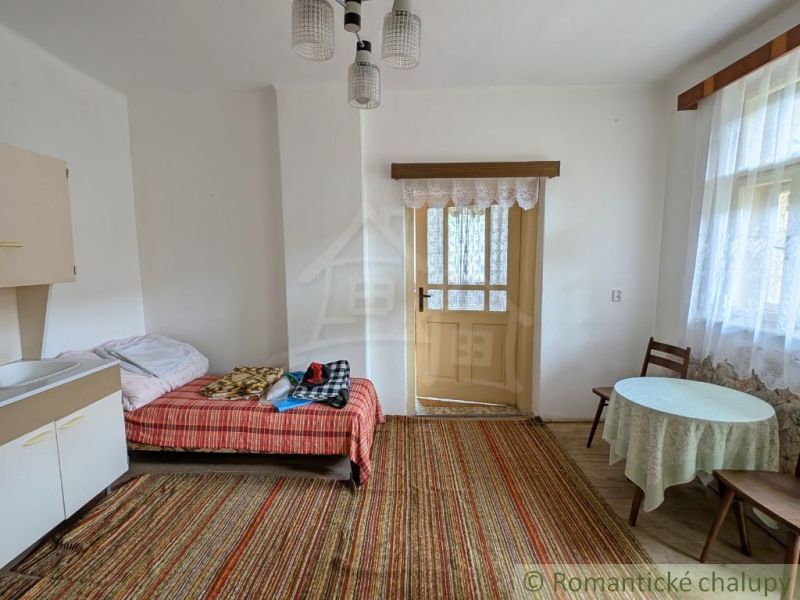 Interior of a family house with a bed, table, and carpet.