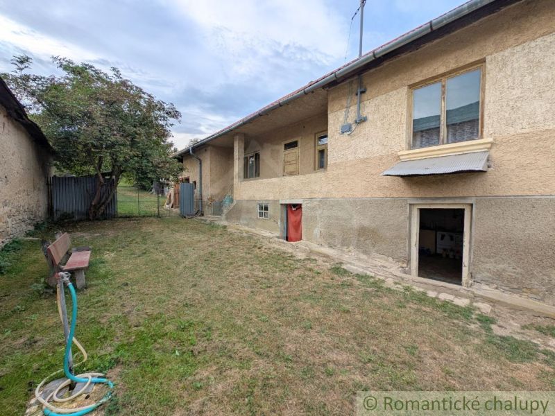 A family house in Nižné Ladičkovce, simple exterior, garden with lawn and bench.
