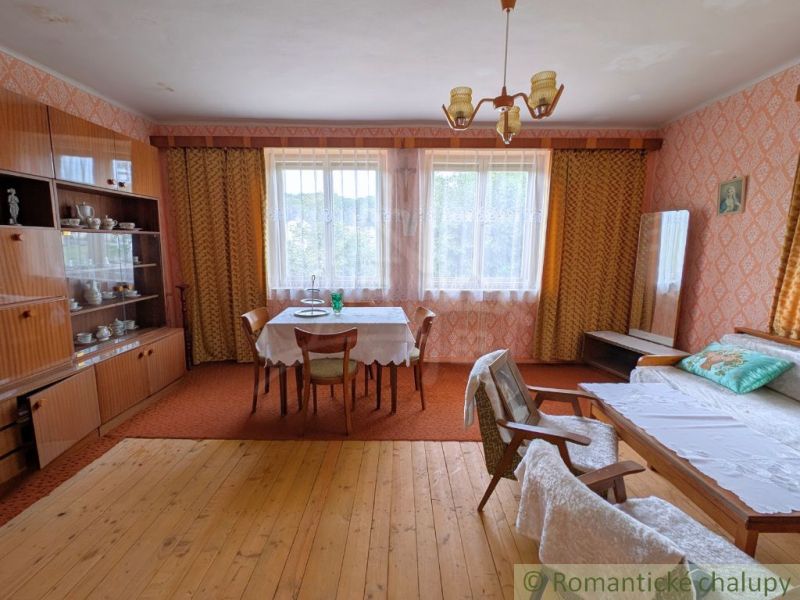 Living room with retro furniture, wood-patterned flooring, and floral curtains in a family house.