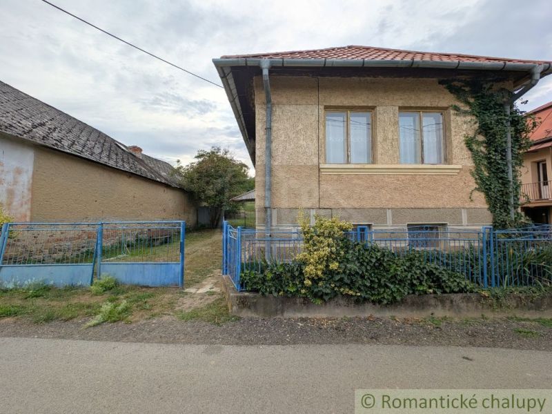 A family house in Nižné Ladičkovce with a blue fence and a garden behind the house.