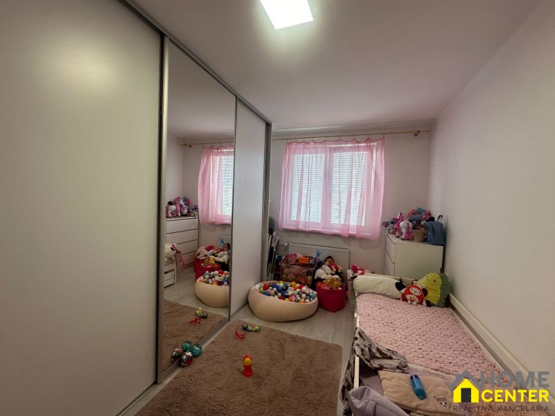 A room in a 3-room apartment with pink curtains, a wardrobe, and children's toys on the floor.