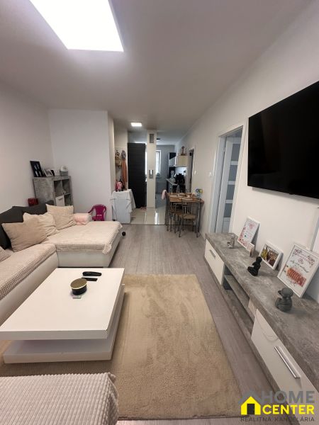 Living room with wood-patterned flooring in a 3-room apartment, with a sofa and a television.