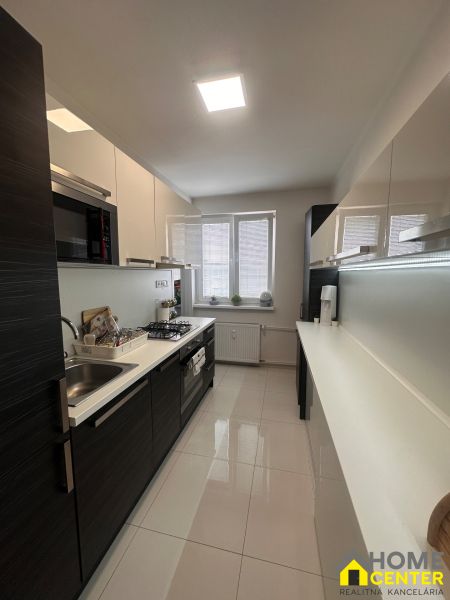 A kitchen in a 3-room apartment with built-in appliances and white tiles.