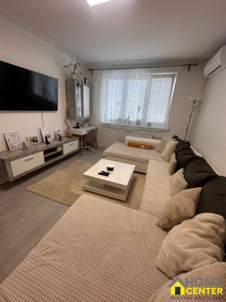 Living room in a 3-room apartment with a sofa, television, and table, floor with wooden decor.