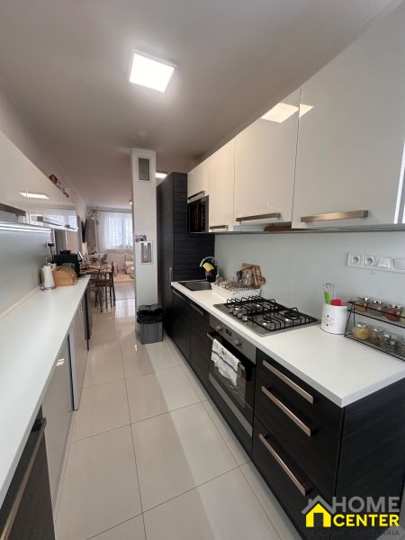 A kitchen in a 3-room apartment with glossy cabinets and white tiles.