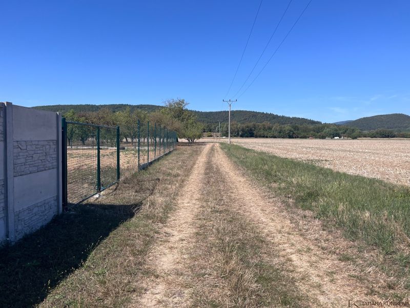 A dirt road in Dulov next to a fence and a large plot, ideal for living.