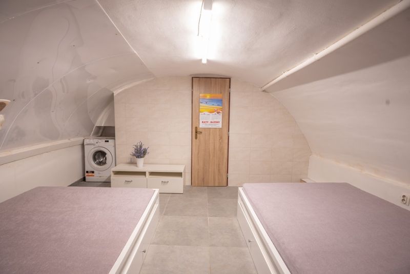 Attic room in a family house with beds, a cabinet, and a washing machine.
