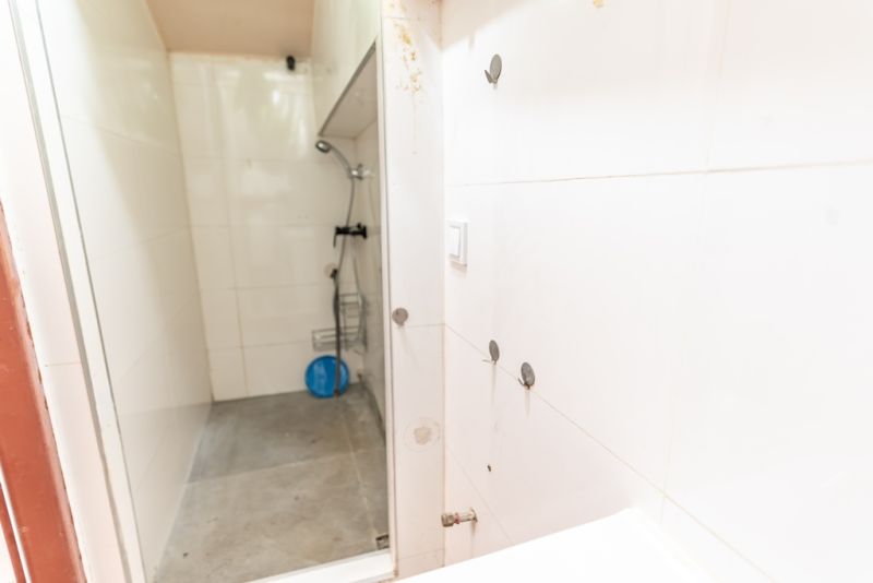 Shower corner with white tiles in the bathroom of a family house.