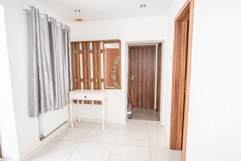 A hallway in a family house with white walls, curtains, and wooden doors.