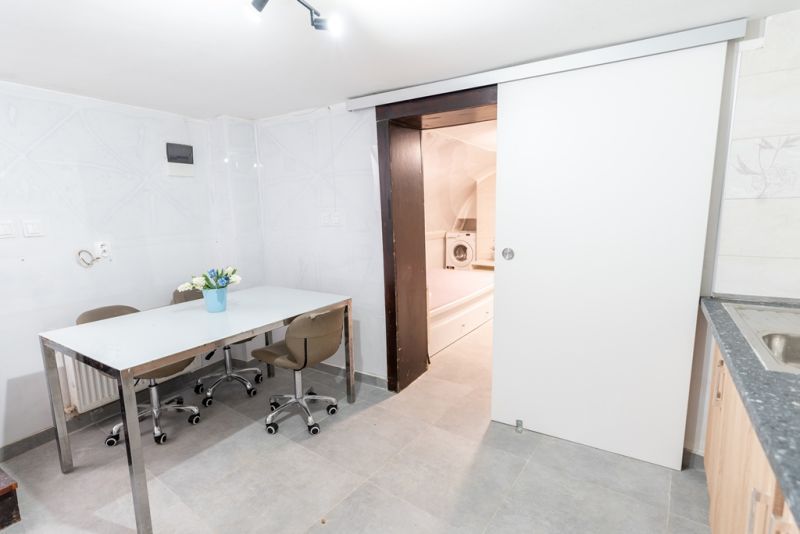 A room in a family house with a white table, chairs, and sliding doors to the laundry room.
