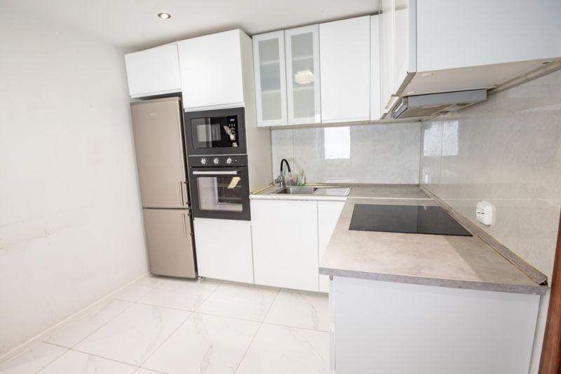 A kitchen in a family house with white cabinets, built-in appliances, and tiles.