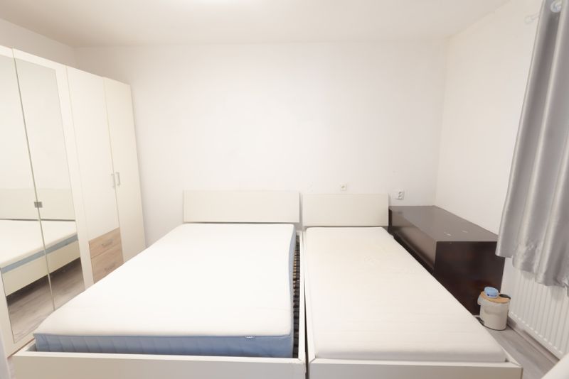 A bedroom in a family house with two beds, a large wardrobe, and simple furniture.