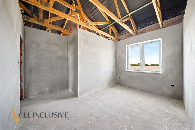 The interior of a family house with wooden beams and a large window, walls with plaster.