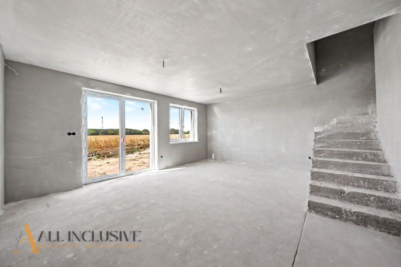 An empty interior of a family house with concrete stairs and large windows.