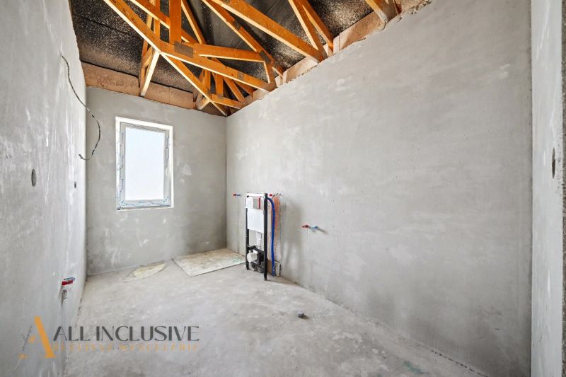 An empty room in a family house with an exposed roof structure.