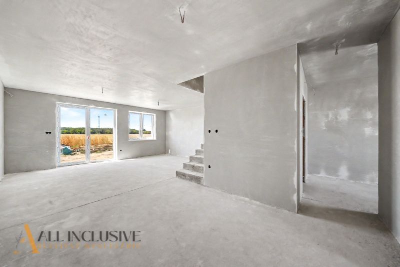 A view into the interior of a family house with a concrete floor and stairs.