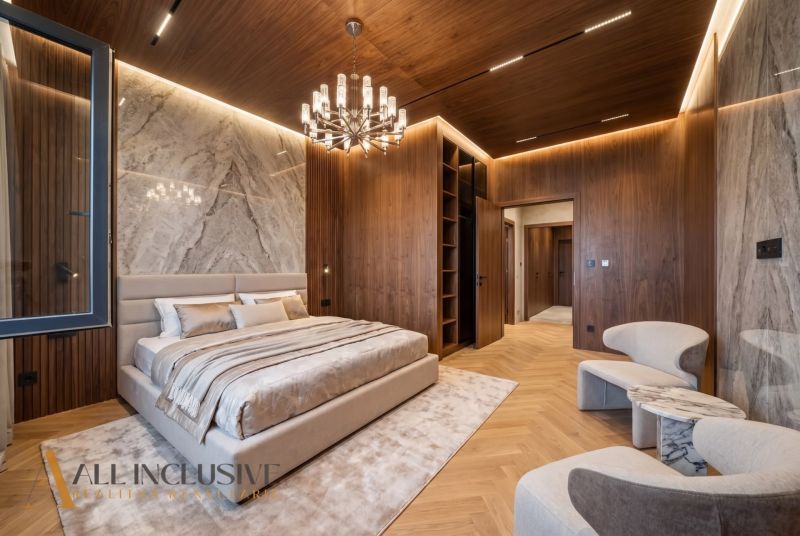 A bedroom in a family house with a wooden decor floor, marble tiles, and an elegant chandelier.