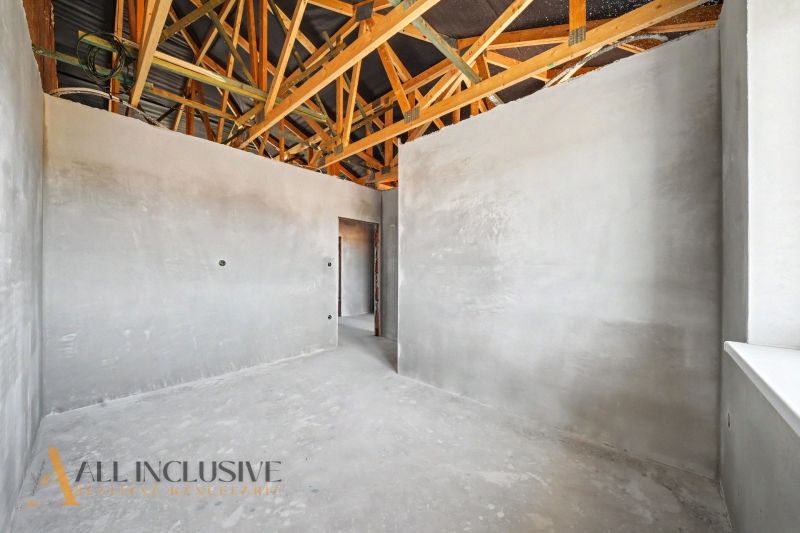 Interior of a family house with raw walls and exposed wooden beams on the ceiling.