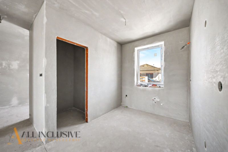 A room in a family house with gray walls, a window, and only basic finishing.