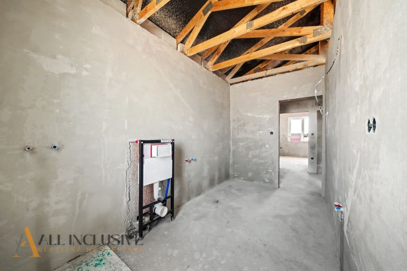 The interior of a house under construction with visible wooden beams and toilet installation.