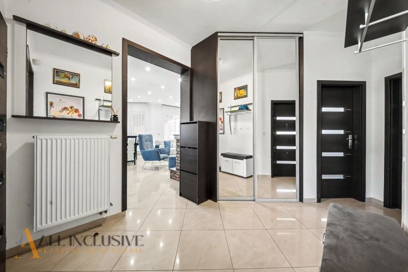 Entrance hall in a family house with tiles, a mirror, and dark doors.