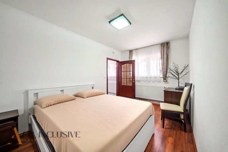 A bright bedroom with a comfortable bed and a wooden decor floor in a family house.