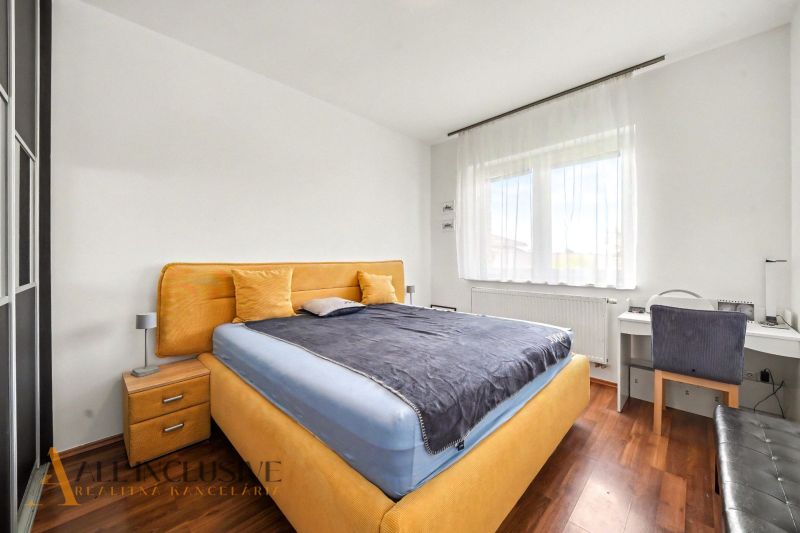 Bedroom in a family house with a wooden decor floor, contains a bed and a work desk.