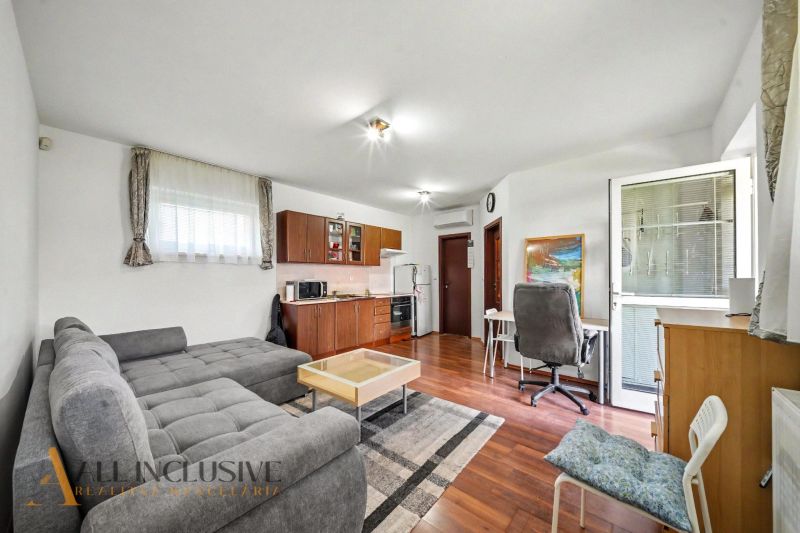 Living room with kitchen, sofa, and wooden decor flooring in a family house.