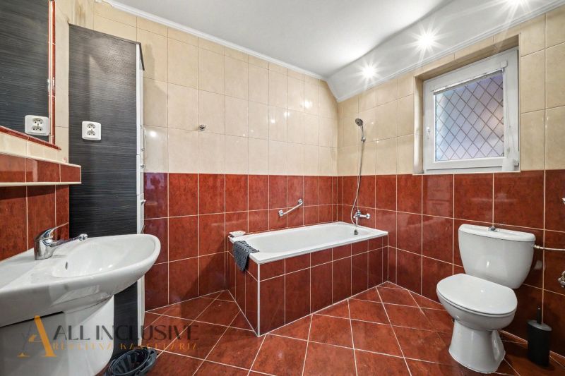 A bathroom in a family house with a bathtub, sink, and toilet, red tiles.
