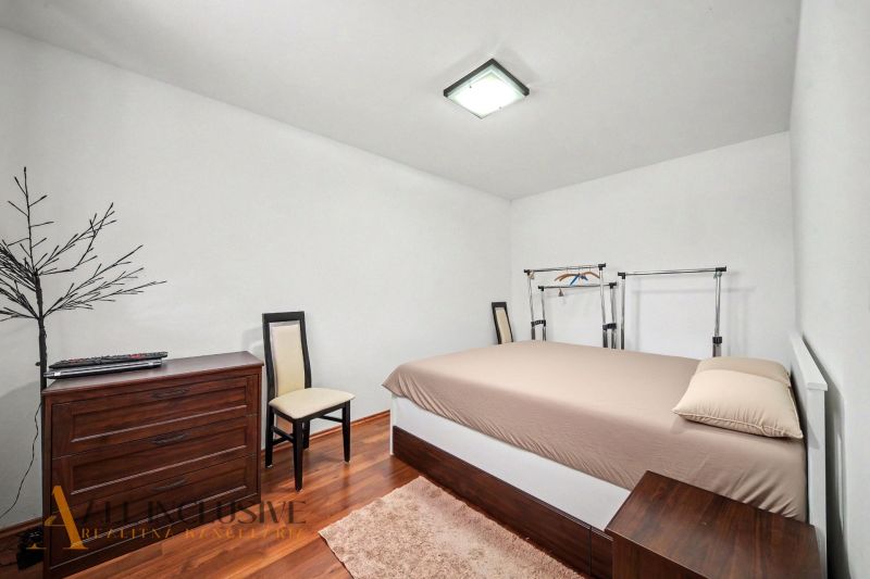 Bedroom with a bed, drawer chest, and wooden decor flooring in a family house.