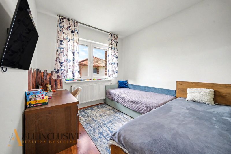 Children's room with two beds, a television, and a wooden decor floor in a family house.