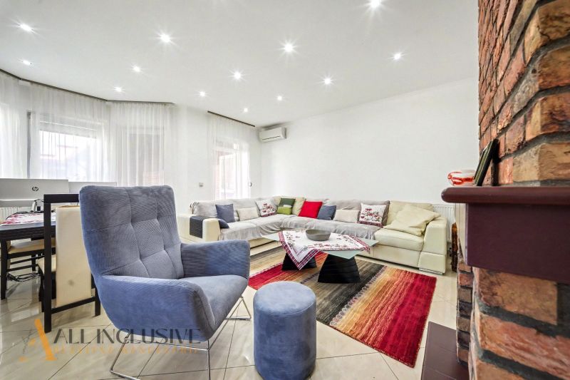 Living room in a family house with a spacious sofa, an armchair, and a decorative carpet.