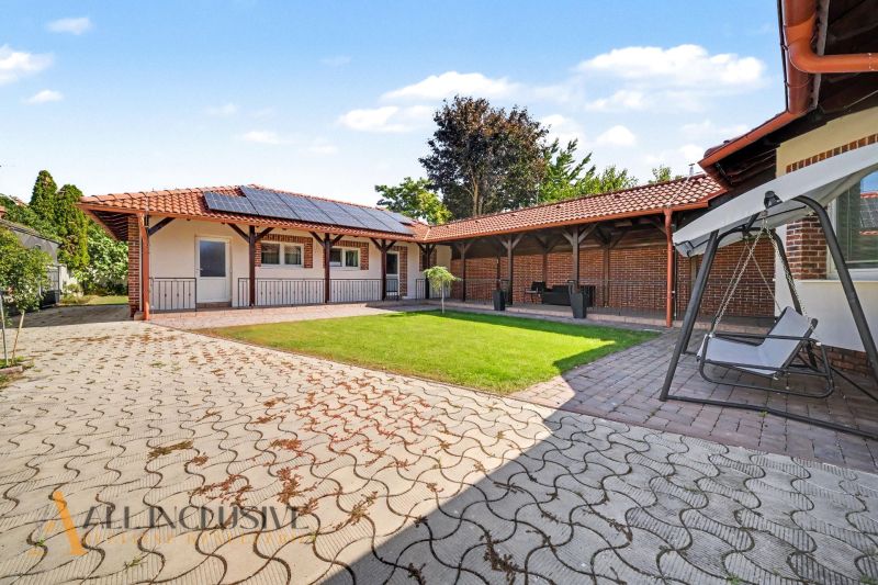 A family house in Kostolné Kračany with a yard, lawn, swing bench, and solar panels.