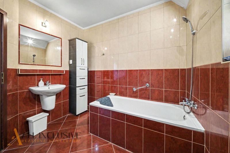 A bathroom in a family house with a bathtub, a sink, and a cabinet, tiled.