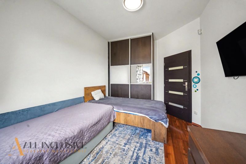A bedroom with two beds and a built-in wardrobe in a family house with a wooden decor floor.