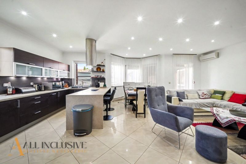 Living room in a family house with a kitchen, dining area, and a light-colored sofa.