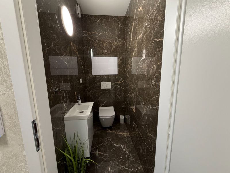 Bathroom in a 2-room apartment with a mirror, sink, and marble tiles.