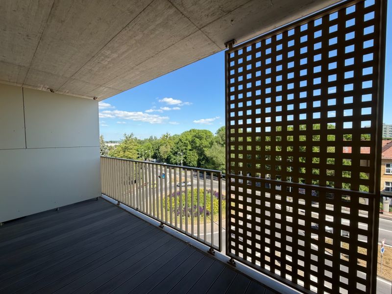 A balcony with a wooden floor and a view of Main Street in Galanta.