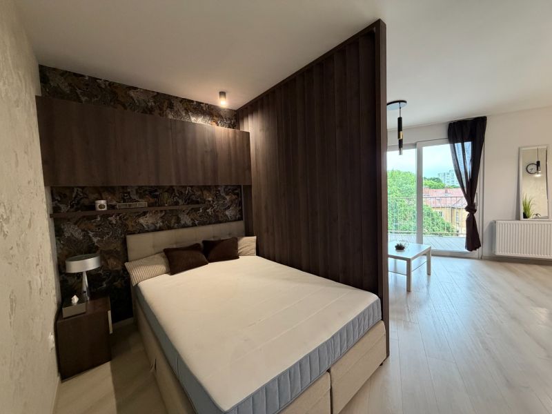 Bedroom in a 2-room apartment, bed, space with separate living area and balcony.