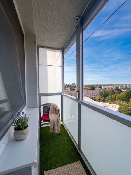 Balcony of a 3-room apartment in Šaľa with a view of the city, a flower pot, and a chair.
