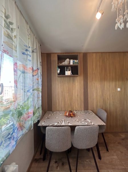 A dining room with wooden decor, a patterned table, and floral curtains in a 3-room apartment.