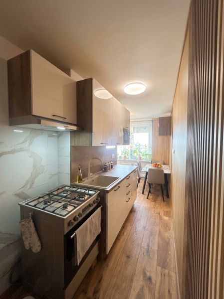 A kitchen in a 3-room apartment with a wooden decor floor and a dining area.
