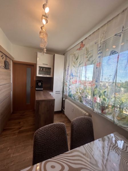 Bright kitchen in a 3-room apartment with a wooden decor floor and colorful curtains.