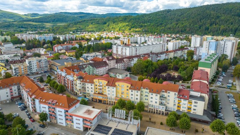 Púchov, Moyzesova Street: apartment buildings surrounded by greenery and commercial spaces in the background of nature.