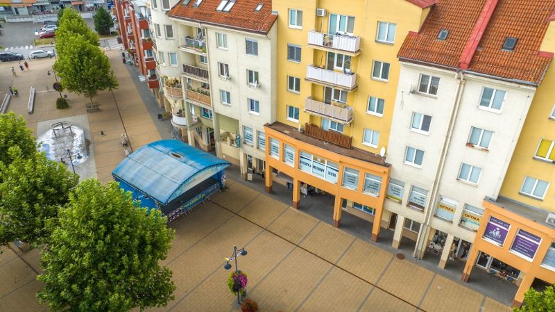 A building with commercial spaces on Moyzesova Street in Púchov, lined with trees.