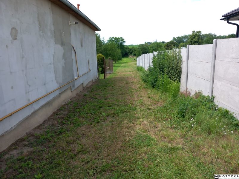 The back part of the building enclosed by a fence in Beladice, suitable for residential plots.