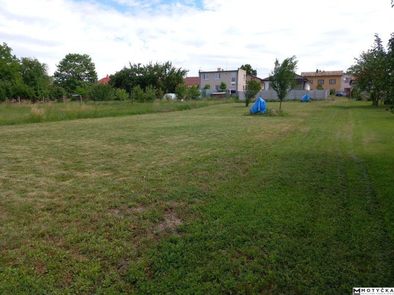 A garden with a lawn surrounded by houses in Beladice, designated for residential plots.