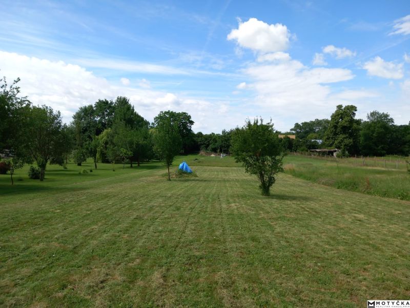 A plot for residential use in Beladice with maintained grass and scattered trees.