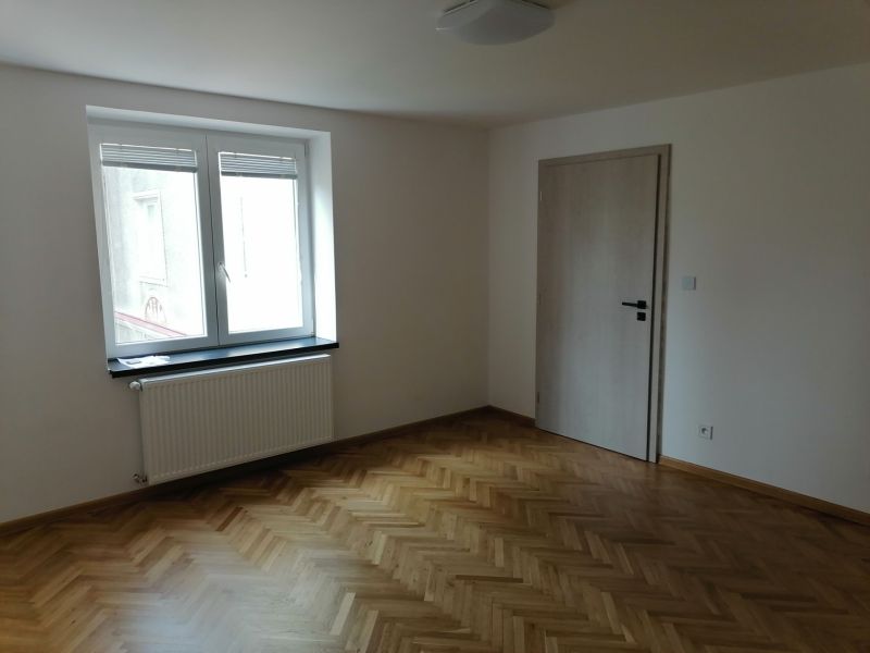 A room with a wooden decor floor and a window in a 2-room apartment.